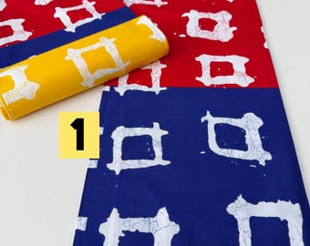 May include: A colorful fabric with a repeating white square design on red, yellow, and blue backgrounds. A rolled-up piece of yellow fabric with the same pattern is also present. The fabric is likely for sewing or crafting.