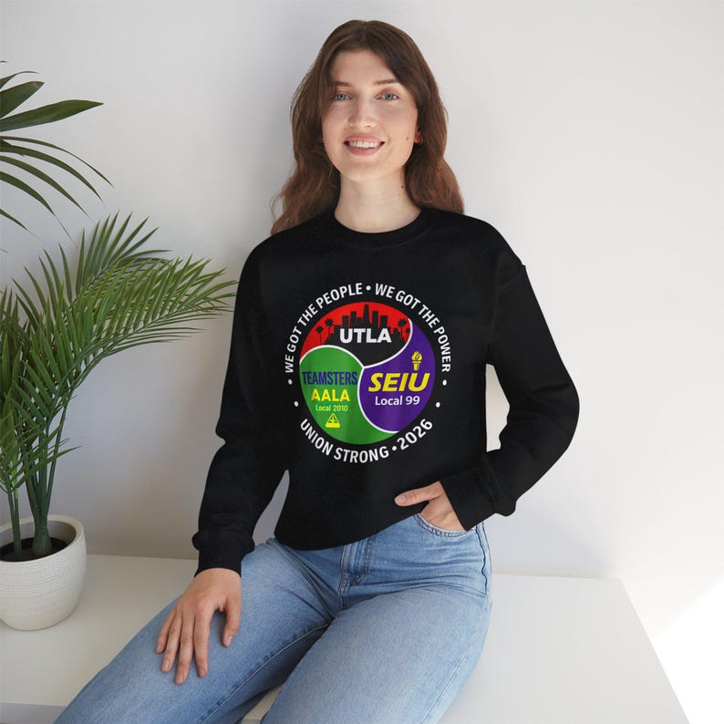 May include: Black sweatshirt with a circular graphic featuring the text "WE GOT THE PEOPLE WE GOT THE POWER" and the words "UTLA", "TEAMSTERS AALA Local 2010", and "SEIU Local 99". The graphic also includes the words "UNION STRONG 2026".