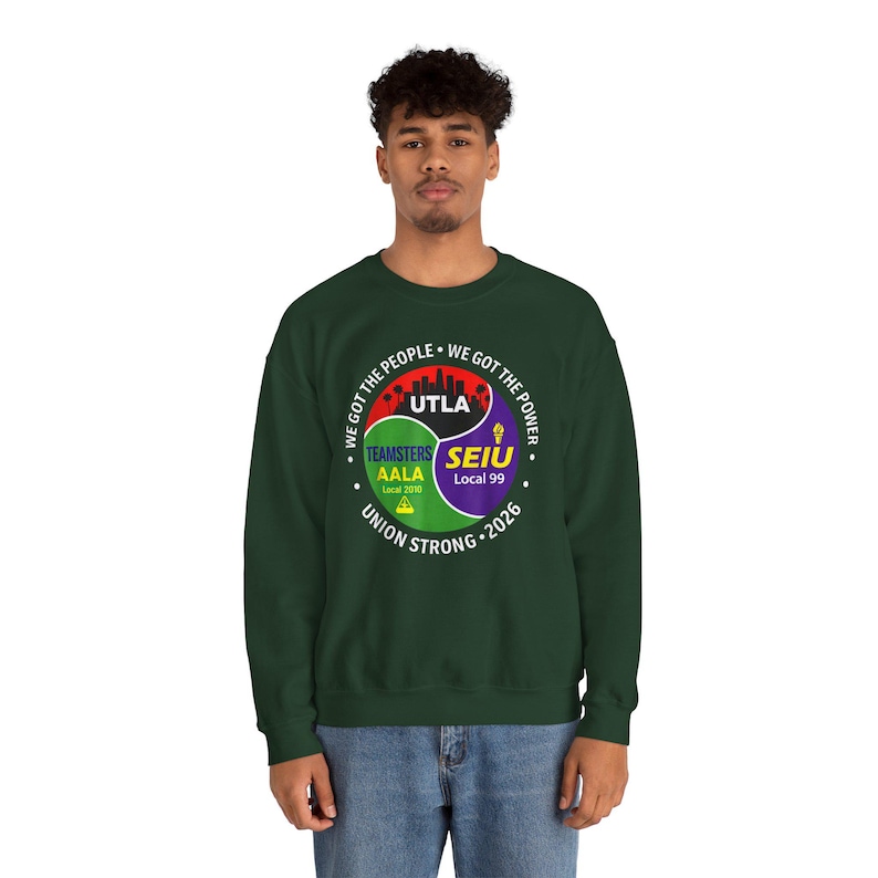 May include: A dark green sweatshirt with a circular graphic featuring the text "WE GOT THE PEOPLE" and "WE GOT THE POWER". The graphic includes the words "UTLA", "TEAMSTERS AALA Local 2010", and "SEIU Local 99". The words "UNION STRONG 2026" are also present.
