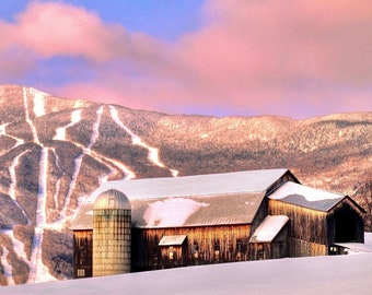 May include: A wooden barn with a silo in front of it, set against a backdrop of snow-covered mountains with ski trails. The sky is a soft pink and purple.