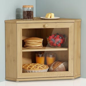 May include: A light-colored wooden corner cabinet with a glass door, displaying pancakes, fruit, juice, and bread. A jar of coffee beans and butter are on top. The cabinet has a round wooden knob.