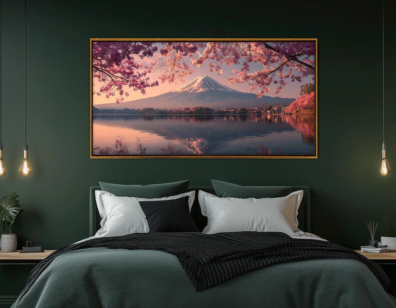 May include: A framed landscape print featuring Mount Fuji reflected in a lake, under a sky with pink cherry blossoms. The artwork has a gold frame and is displayed above a bed with green bedding.