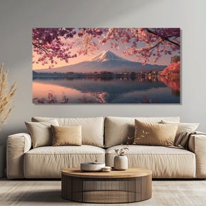 May include: A large canvas print of a serene landscape featuring Mount Fuji. The artwork depicts the mountain reflected in a lake, framed by pink cherry blossoms. The sky transitions from pink to blue, creating a tranquil scene.