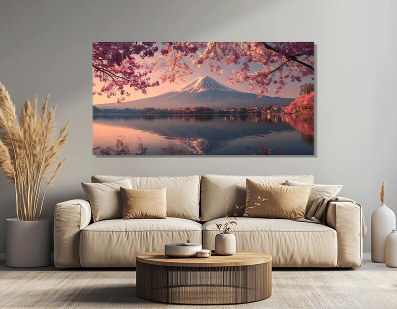May include: A large canvas print of a serene landscape featuring Mount Fuji. The artwork depicts the mountain reflected in a lake, framed by pink cherry blossoms. The sky transitions from pink to blue, creating a tranquil scene.