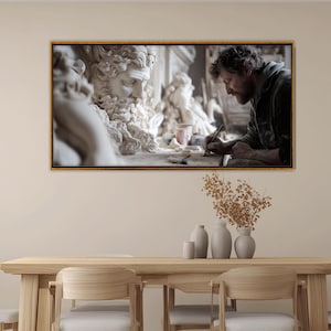 Peut inclure: Une œuvre encadrée représente un sculpteur travaillant sur un buste classique. L'artiste, vêtu d'une veste sombre, est concentré sur son travail. Le buste est blanc, avec des détails complexes. La scène se déroule dans un atelier.