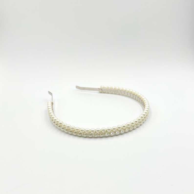 May include: A pearl beaded headband with a silver metal band. The headband is adorned with two rows of small, round, off-white pearls. The design is simple and elegant, suitable for various occasions.