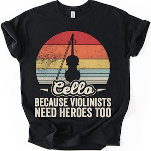 May include: Black t-shirt featuring a cello silhouette against a retro sunset design in red, orange, yellow, and blue stripes. The text reads "Cello BECAUSE VIOLINISTS NEED HEROES TOO" in white, a humorous statement for musicians.