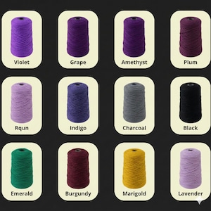 K&ouml;nnte beinhalten: Eine Sammlung von Garnspulen in verschiedenen Farben, darunter Violett, Traube, Amethyst, Pflaume, Rqun, Indigo, Holzkohle, Schwarz, Smaragd, Burgunder, Ringelblume und Lavendel. Jede Spule ist mit ihrem Farbnamen beschriftet.