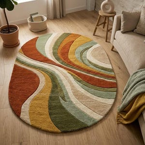 May include: A round area rug with a flowing, abstract design. The rug features curved bands of color in shades of rust, orange, yellow, green, and beige. The rug is placed on a hardwood floor, and the overall aesthetic is modern and inviting.