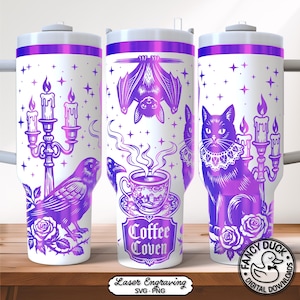 Op de afbeelding: Witte beker met paarse illustraties van een raaf, vleermuis, kat, kaarsen en rozen. De beker heeft een paarse rand en de woorden "Coffee Coven". Het ontwerp is een digitale lasergravure.