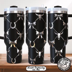 May include: Black tumbler with a silver design featuring bows, horseshoes, and bull skulls. The tumbler has a white lid and a silver rim. The design is repeated across the surface. The bottom of the tumbler has the text "Laser Engraving SVG PNG".
