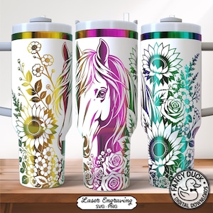 Peut inclure: Trois gobelets isothermes blancs avec des motifs de tête de cheval et de fleurs colorées. Chaque gobelet présente une palette de couleurs différente : or, rose et sarcelle. Les gobelets ont un couvercle blanc et un bord métallique.