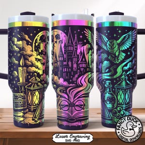 May include: Three black insulated tumblers with iridescent rims and handles. Each tumbler features a different fantasy-themed design in rainbow colours, including a castle, an owl, and a candle. The tumblers are on a wooden surface.
