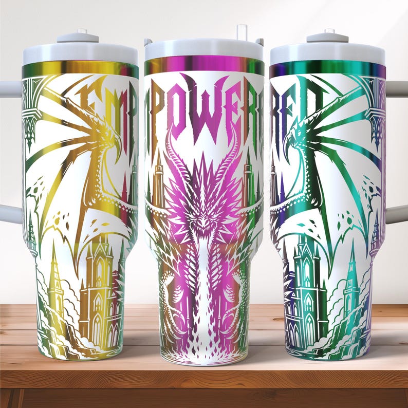 May include: Three white insulated tumblers with colorful dragon and castle designs. Each tumbler features the word "EMPOWERED" in a bold, stylized font. The dragons and castles are rendered in shades of gold, purple, and green.