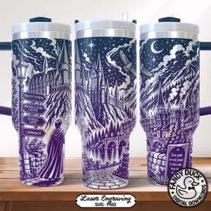 Puede incluir: Un vaso de acero inoxidable con un diseño grabado con láser. El diseño presenta un castillo, montañas y un cielo nocturno con estrellas y una luna. El vaso también incluye un letrero con nombres de pueblos y una persona con capa.