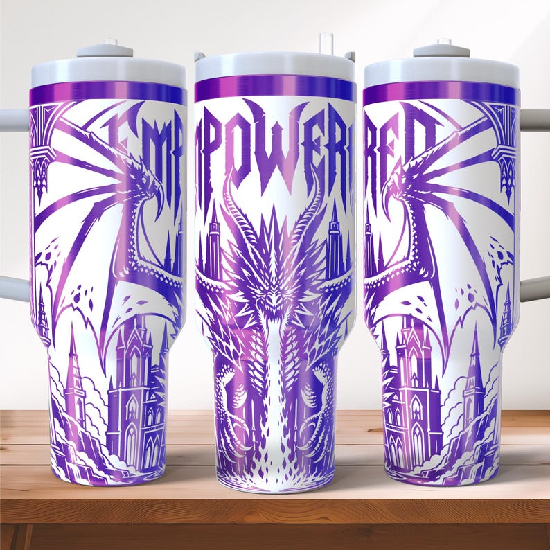 May include: White tumbler with a purple dragon design and the word "EMPOWERED" in purple. The design includes a dragon, castle, and architectural elements. The tumbler has a white lid and a purple rim.