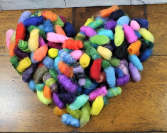 May include: A heart-shaped arrangement of colorful felted wool rovings. The rovings are in various shades of blue, green, purple, pink, yellow, orange, and red.