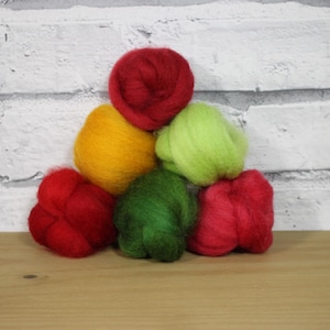 May include: Six balls of wool in various colors, including red, green, and yellow. The balls are arranged in a pyramid shape.