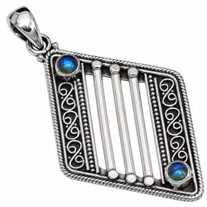 May include: A diamond-shaped silver pendant featuring a rope-textured border, intricate scrollwork, and four vertical silver bars. Two round, iridescent blue labradorite cabochons are set at the top left and bottom right corners of the frame.
