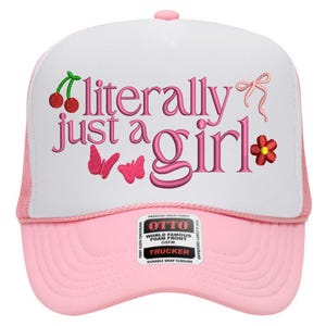 Puede incluir: Gorra de camionero rosa y blanca con el texto bordado "literally just a girl" en rosa. El diseño incluye cerezas, mariposas, un lazo y una flor. La gorra tiene una parte delantera de espuma y cierre a presión.