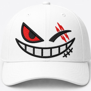 May include: A white baseball cap featuring an embroidered graphic of a stylised face. The design includes a single sharp red and black eye, a wide black grinning mouth with teeth, three red slash marks, and a small black stitched scar detail.