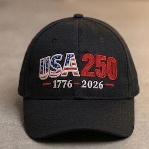 May include: A black baseball cap with the text "USA 250" embroidered in white, red, and blue. The cap features the American flag design within the letters "USA" and the years "1776-2026" below the text.