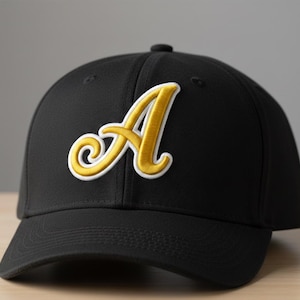 May include: Black baseball cap with a gold embroidered letter "A" outlined in white. The cap has a curved brim and a structured fit, suitable for sports or casual wear.