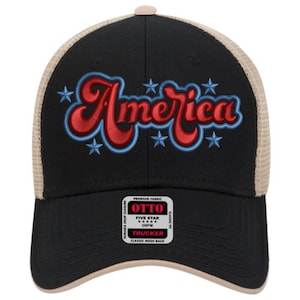 May include: Black trucker hat with a tan mesh back and a curved brim. The front features the word "America" in red script with a blue outline and blue star accents. The hat has a snap closure.