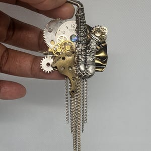 Broszka saksofonowa w stylu steampunk, elementy mechanizmu zegarowego, koła zębate i łańcuchy. Biżuteria artystyczna.