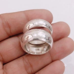 May include: Two polished sterling silver rings with a smooth, rounded dome profile. The inner band of the bottom ring features a clear rectangular stamp with the text 925, indicating the silver purity of the metal used in these jewellery pieces.