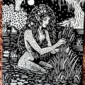 Peut inclure: Illustration en noir et blanc d'une créature mythique dans un marais. La figure a de longs cheveux, des oreilles pointues et des ornements floraux. L'œuvre représente des nénuphars, des roseaux et une pleine lune, créant une scène sereine.