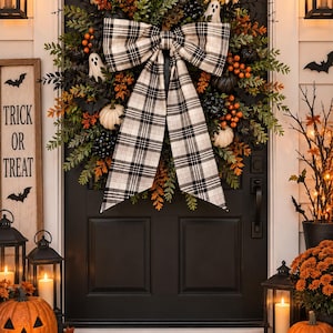 May include: A Halloween wreath featuring green foliage, orange berries, black pumpkins, white ghost figures, and a large black and white plaid bow. The wreath is mounted on a black door above a welcome mat with a pumpkin and lantern display.