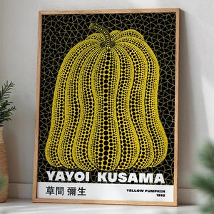 May include: A framed art print featuring a yellow pumpkin with black polka dots against a black background. The print includes the text "YAYOI KUSAMA" and "YELLOW PUMPKIN 1992". The artwork is in a wooden frame.