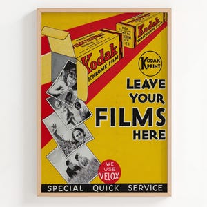 May include: Vintage Kodak film advertisement in a wooden frame. The poster features a yellow background with red diagonal stripes and the text "LEAVE YOUR FILMS HERE." It includes images and boxes of Kodak film.