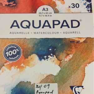 Op de afbeelding: AQUAPAD aquarel papierblok, A3 formaat, 29,7 x 42 cm, 300 g/m², met 30 vellen. Het papier is koudgeperst en heeft een kleurrijk aquarelontwerp. Inclusief een sticker met productdetails.