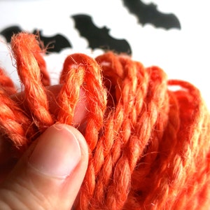 Puede incluir: Primer plano de una bola de hilo naranja. El hilo es suave y esponjoso, perfecto para manualidades.