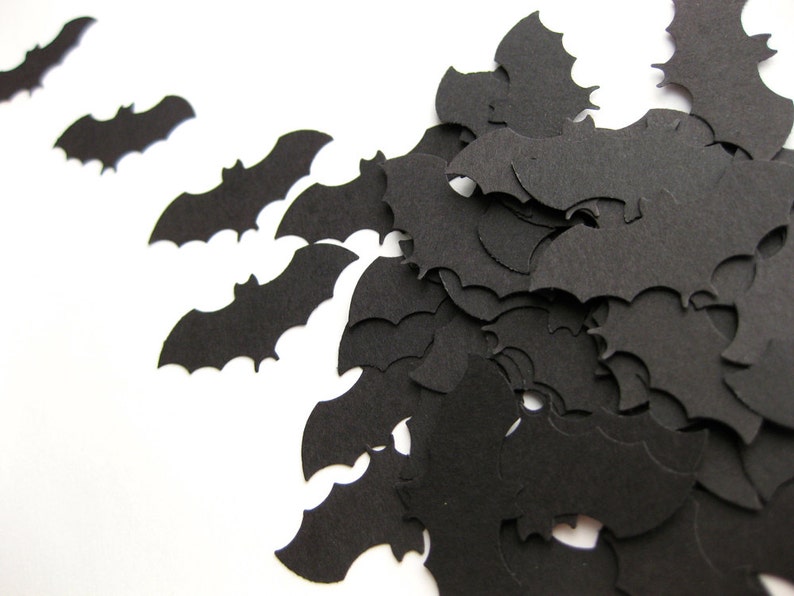 K&ouml;nnte beinhalten: Schwarze Papierflederm&auml;use, die auf einem wei&szlig;en Hintergrund verstreut sind. Die Flederm&auml;use sind in verschiedenen Gr&ouml;&szlig;en und Positionen angeordnet und schaffen eine festliche Halloween-Atmosph&auml;re.