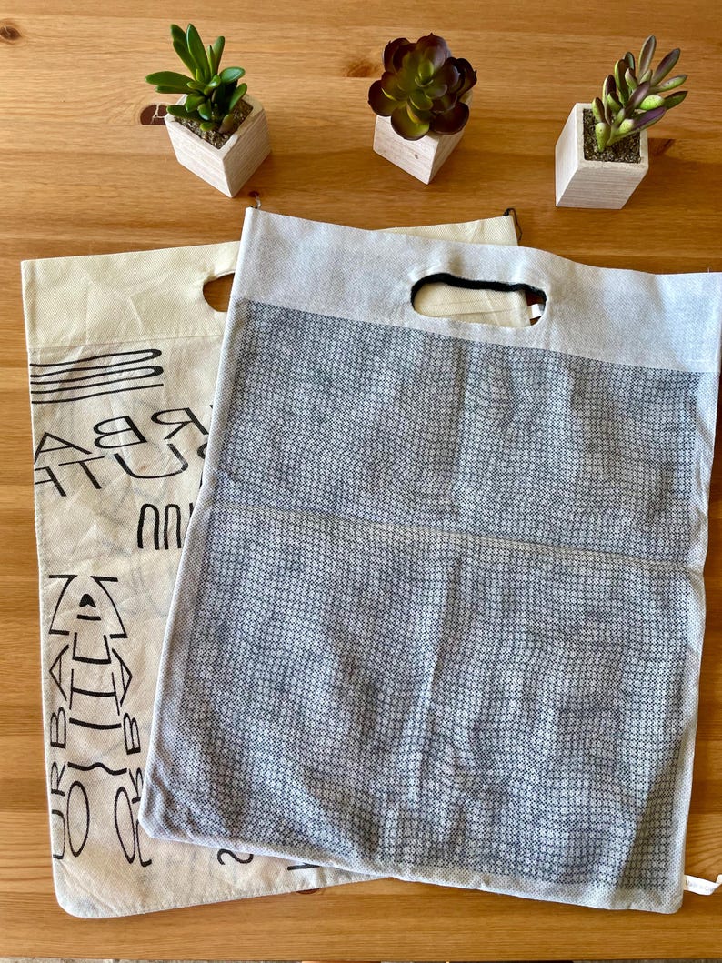 May include: Two reusable shopping bags. One is a beige canvas bag with black text and a black mesh pocket. The other is a gray mesh bag with a black handle.