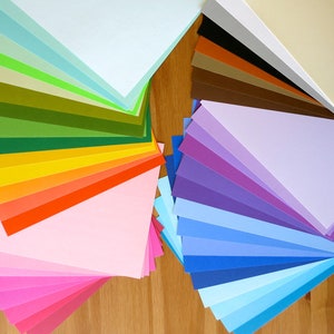 K&ouml;nnte beinhalten: Eine Sammlung bunter Papierb&ouml;gen, die in Form eines F&auml;cher angeordnet sind. Die Farben reichen von Hellblau bis Dunkelblau, von Hellgr&uuml;n bis Dunkelgr&uuml;n und von Hellrosa bis Dunkelrosa. Die Papierb&ouml;gen sind in zwei Gruppen angeordnet, eine links und eine rechts.