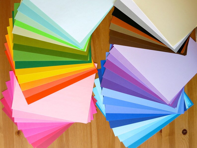K&ouml;nnte beinhalten: Eine Sammlung bunter Papierb&ouml;gen, die in Form eines F&auml;cher angeordnet sind. Die Farben reichen von Hellblau bis Dunkelblau, von Hellgr&uuml;n bis Dunkelgr&uuml;n und von Hellrosa bis Dunkelrosa. Die Papierb&ouml;gen sind in zwei Gruppen angeordnet, eine links und eine rechts.
