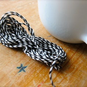 Puede incluir: Primer plano de un cordel negro y blanco, un tipo de cuerda que se utiliza para envolver y atar.