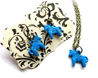 May include: A set of blue horse charm earrings and a matching necklace. The charms are made of metal and have a distressed finish. The earrings are on a card with a black and white floral pattern.