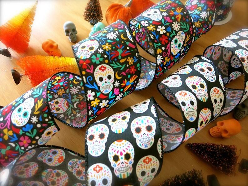 Puede incluir: Cinta negra y blanca con un patr&oacute;n de calavera de az&uacute;car colorido. La cinta est&aacute; decorada con flores y espirales.