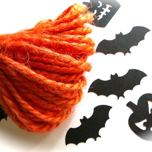 Puede incluir: Una bola de hilo naranja con recortes de papel negro de murci&eacute;lagos y calabazas.