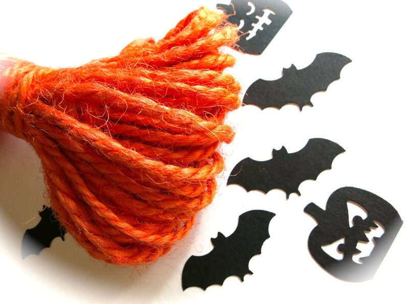 Puede incluir: Una bola de hilo naranja con recortes de papel negro de murci&eacute;lagos y calabazas.
