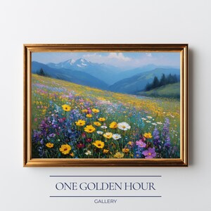 May include: A framed landscape painting depicts a vibrant meadow filled with yellow, white, and purple wildflowers. The background features rolling green hills and blue mountains under a clear sky. The painting is in a gold frame. Text at the bottom reads "ONE GOLDEN HOUR GALLERY."
