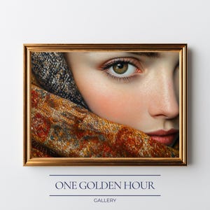 May include: A framed portrait featuring a close-up of a person's face, with a focus on the eye and part of the face. The person is partially covered by a patterned scarf. The frame is gold, and the text "ONE GOLDEN HOUR GALLERY" is at the bottom.