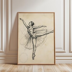 May include: A framed sketch of a ballerina in a graceful pose. The artwork is in black and white, with delicate lines capturing the dancer's form and flowing tutu. The frame is a warm, natural wood tone, and the background is a vintage-style beige.