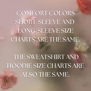 May include: Image with text: "COMFORT COLORS SHORT-SLEEVE AND LONG-SLEEVE SIZE CHARTS ARE THE SAME. THE SWEATSHIRT AND HOODIE SIZE CHARTS ARE ALSO THE SAME." Soft, blurred background with pink and white flowers.