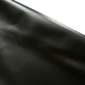 May include: A close-up of a black, smooth, and shiny fabric. The fabric is folded over on itself, creating a crease.